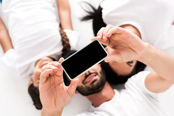 Top view of happy bearded man holding smartphone with blank screen near wife and kid isolated on white — Stock Photo