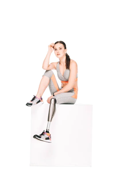 Disabled sportswoman with prosthetic leg sitting isolated on white — Stock Photo