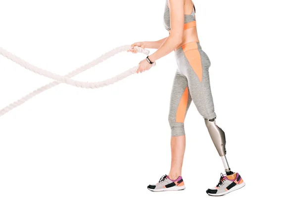 Cropped view of disabled sportswoman with prosthetic leg training with ropes isolated on white — Stock Photo