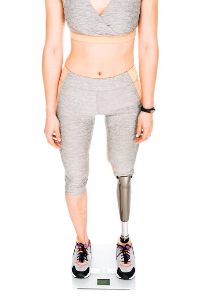 Частичный вид спортсменки-инвалида с протезной ногой на взвешивающей шкале, изолированной по белому — стоковое фото