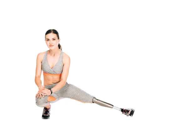 Disabled sportswoman with prosthesis stretching isolated on white — Stock Photo