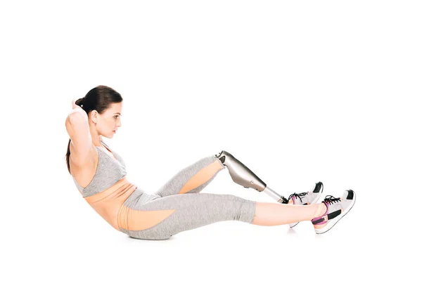 Vue latérale d'une sportive handicapée avec prothèse faisant des redressements assis isolés sur du blanc — Photo de stock