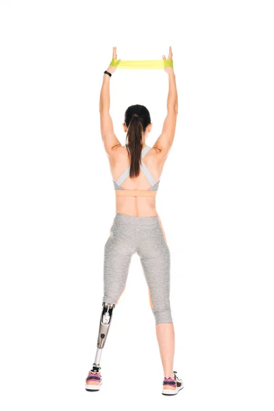 Back view of disabled sportswoman with prosthesis training with resistance band isolated on white — Stock Photo