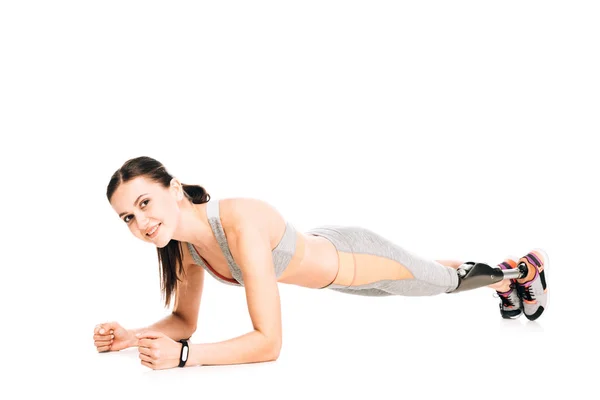 Smiling disabled sportswoman with prosthesis standing in plank isolated on white — Stock Photo