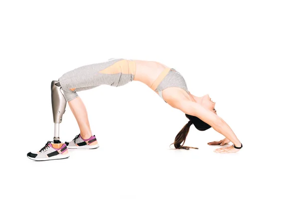 Вид сбоку спортсменки-инвалида с протезом, выполняющей мостовые упражнения изолированные на белом — стоковое фото