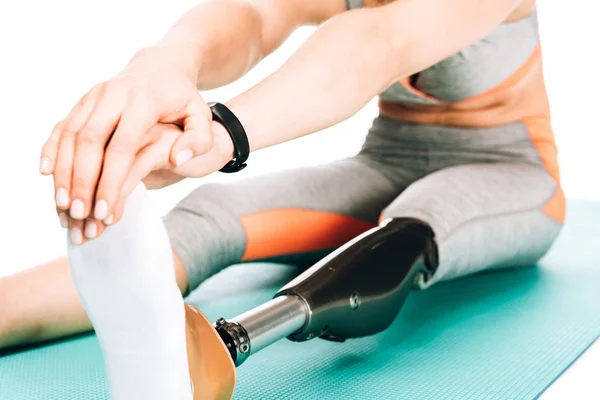 Cropped view of disabled sportswoman stretching on fitness mat isolated on white — Stock Photo