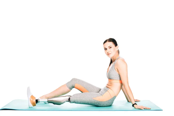 Mulher deficiente em sportswear sentado no tapete de fitness isolado no branco — Fotografia de Stock