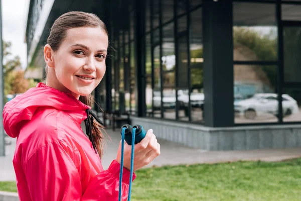 Sorrindo atraente desportista segurando pulando corda na rua — Fotografia de Stock