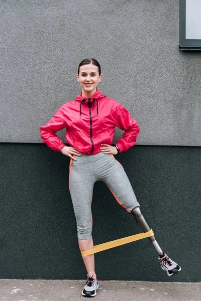 Full length view of disabled sportswoman training with resistance band on street — Stock Photo