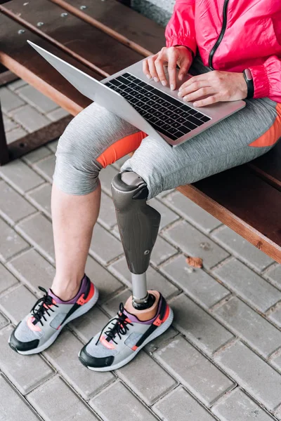 Partial view of disabled sportswoman typing on laptop on street — Stock Photo