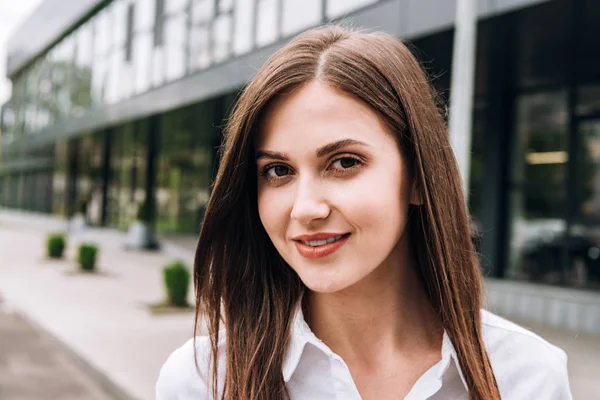 Приваблива молода жінка в білій сорочці посміхається на вулиці — стокове фото
