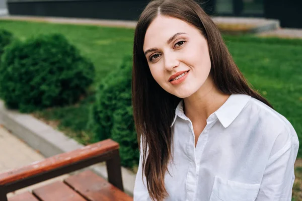 Jolie jeune femme souriante en chemise blanche sur la rue — Photo de stock