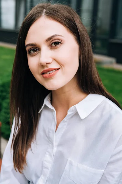 Jolie jeune femme souriante en chemise blanche sur la rue — Photo de stock