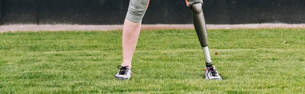 Panoramic shot of disabled sportswoman standing on grass — Stock Photo