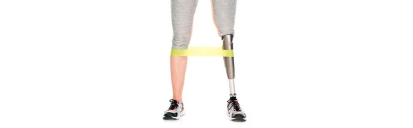 Panoramic shot of disabled sportswoman with prosthetic leg training with resistance band isolated on white — Stock Photo