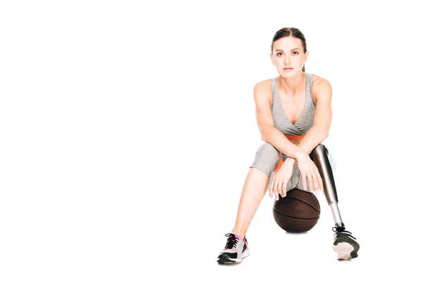 Vorderseite der behinderten Sportlerin sitzt auf Basketballball isoliert auf weiß — Stockfoto