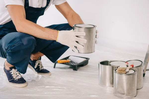 Cropped view of painter in uniform holding can with paint — Stock Photo