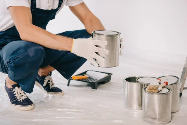 Recortado vista de pintor en uniforme celebración lata con pintura - foto de stock