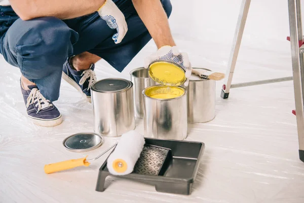 Vista parcial del pintor en lata de apertura uniforme con pintura amarilla - foto de stock