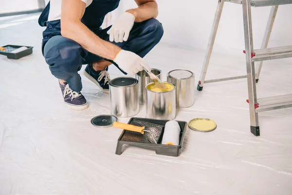 Cropped view of painter taking yellow paint from can with paintbrush — Stock Photo