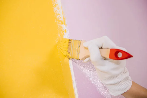 Vue partielle du mur de peinture peintre en jaune et rose avec pinceau — Photo de stock