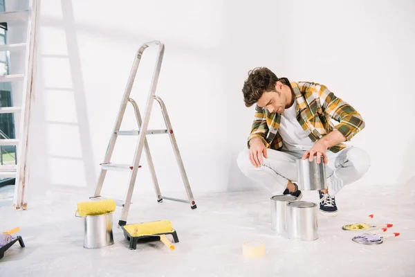 Junger Mann hält Dose mit Farbe in der Hand, während er sich auf Wandmalerei vorbereitet — Stockfoto