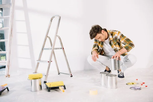 Jeune homme tenant peut avec de la peinture tout en se préparant pour la peinture murale — Photo de stock