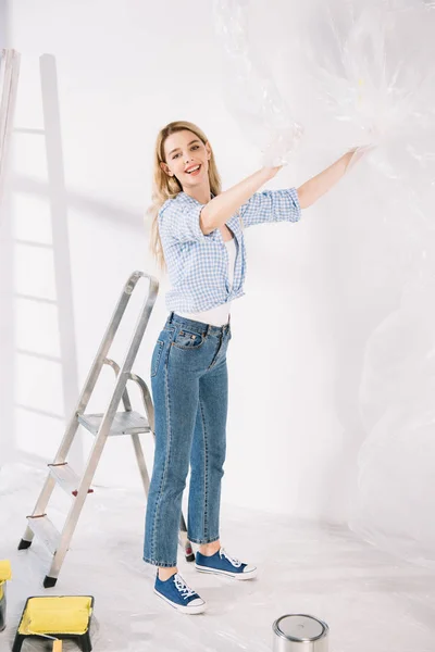 Schöne junge Frau hält Zellophan in der Hand, während sie sich auf Wandmalerei vorbereitet — Stockfoto