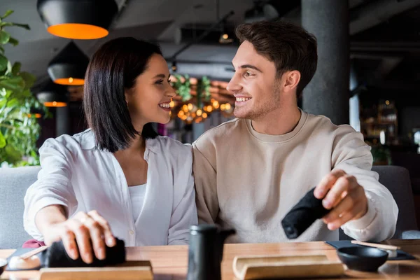 Enfoque selectivo de hombre feliz sosteniendo servilleta negra y mirando a la mujer sonriente - foto de stock