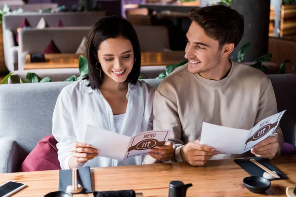 Handsome man looking at happy woman smiling holding holding menu — Stock Photo