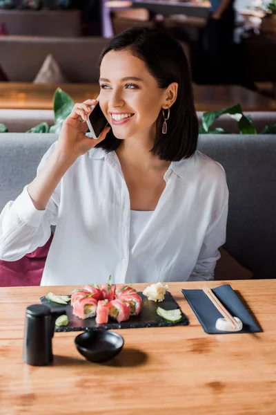 Mulher feliz falando no smartphone no bar de sushi — Fotografia de Stock