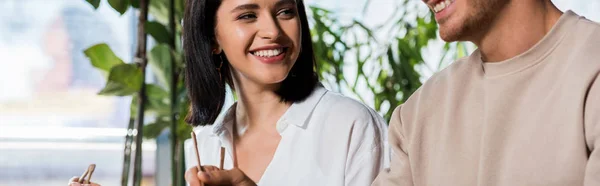 Panoramic shot of happy woman holding chopsticks near man — Stock Photo