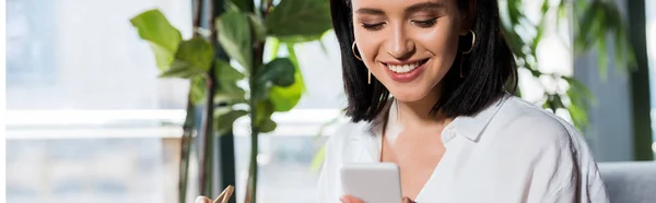 Plano panorámico de la niña usando el teléfono inteligente mientras sostiene palillos - foto de stock