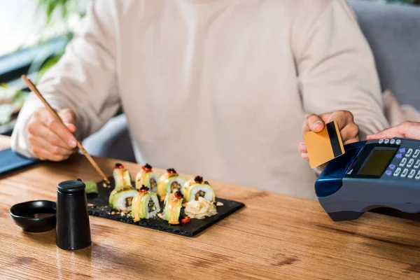 Cropped view of waitress holding payment terminal near man with credit card — Stock Photo