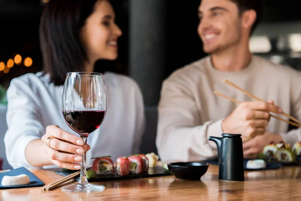 Selektiver Fokus von Mädchen, die Glas mit Rotwein in der Nähe eines glücklichen Mannes berühren — Stockfoto