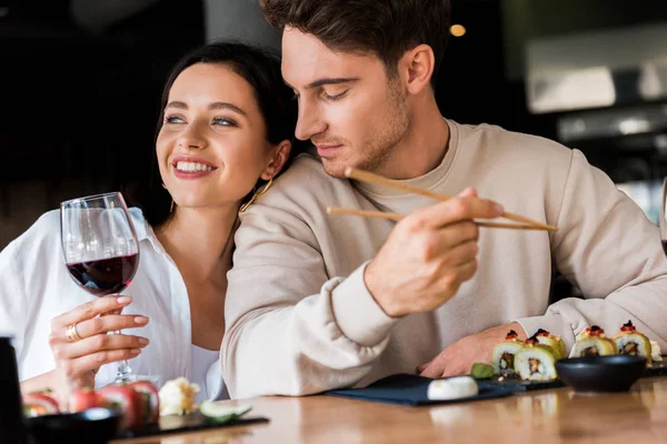 Schöner Mann schaut Frau mit Glas Rotwein an — Stockfoto