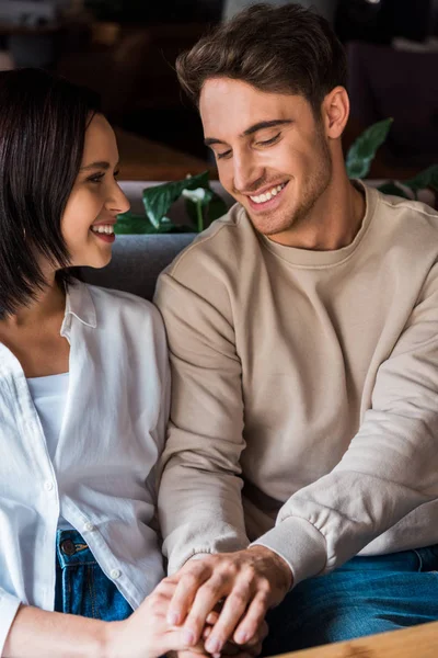 Happy man holding hands with cheerful girlfriend in restaurant — Stock Photo