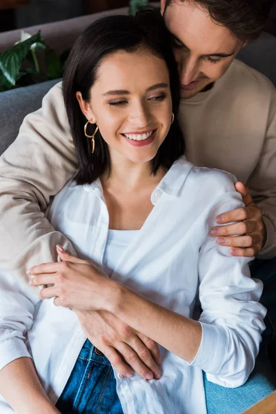 Feliz hombre abrazando alegre novia en restaurante - foto de stock