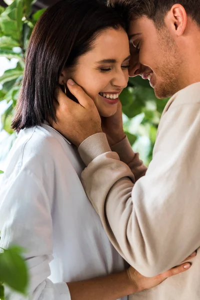 Happy man with closed eyes hugging cheerful girlfriend in restaurant — Stock Photo