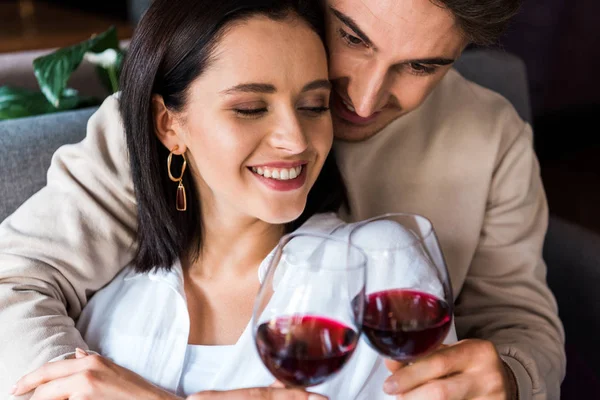 Felice uomo in possesso di vetro con vino rosso vicino ragazza allegra — Foto stock