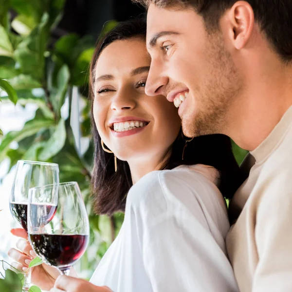Щасливий чоловік тримає келих з червоним вином біля красивої дівчини — стокове фото