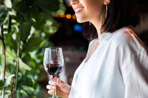 Cropped view of cheerful woman holding glass of red wine — Stock Photo