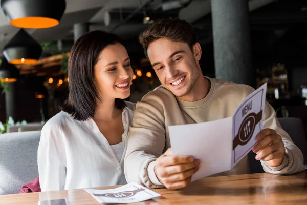 Homem feliz e mulher olhando para o menu no restaurante — Fotografia de Stock