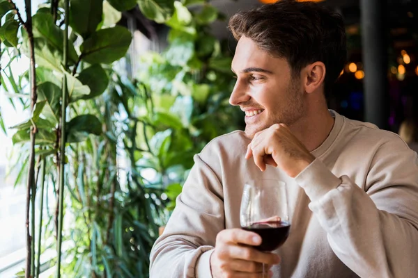 Счастливый человек держит бокал с красным вином в ресторане — стоковое фото