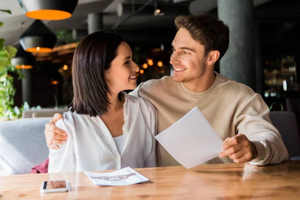 Селективное внимание счастливого мужчины и женщины, улыбающихся в ресторане — стоковое фото