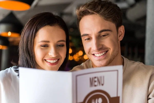 Вибірковий фокус щасливого чоловіка і весела жінка тримає меню — стокове фото
