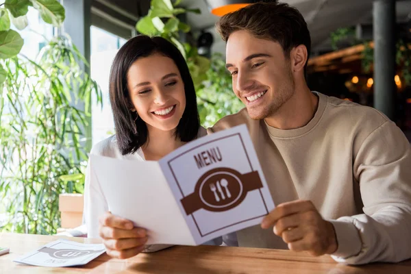 Messa a fuoco selettiva di uomo felice e donna allegra guardando il menu — Foto stock