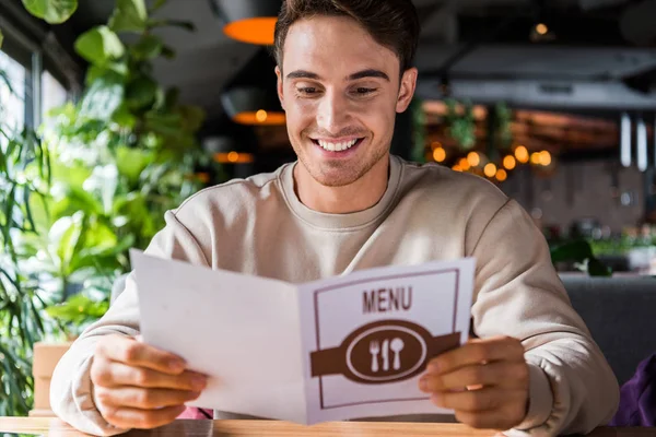Foco seletivo do homem feliz olhando para o menu no restaurante — Fotografia de Stock