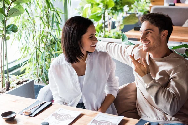 Glückliche Frau blickt Mann gestikulierend in Sushi-Bar an — Stockfoto