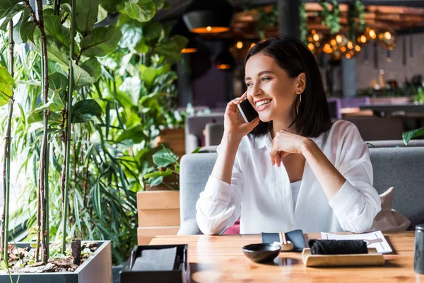 Atractiva mujer sonriendo mientras habla en teléfono inteligente - foto de stock